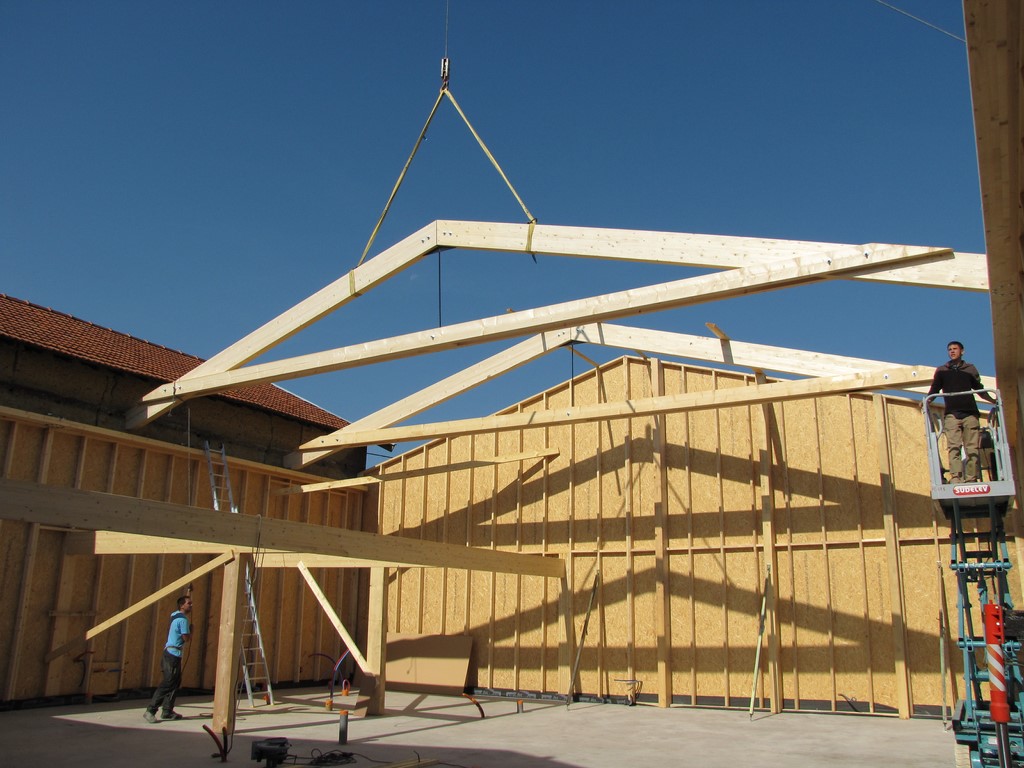 Levage d’une charpente traditionnelle en bois sur une maison en ossature bois