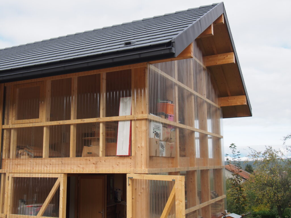 Maison ossature bois isolée en ouate de cellulose avec bardage Mélèze et Polycarbonate.