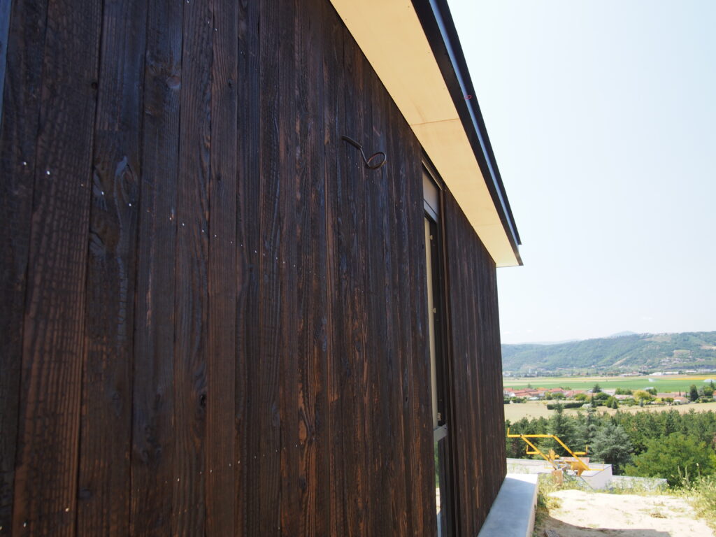 Maison contemporaine ossature bois avec grandes baies vitrées et bardage bois brûlé