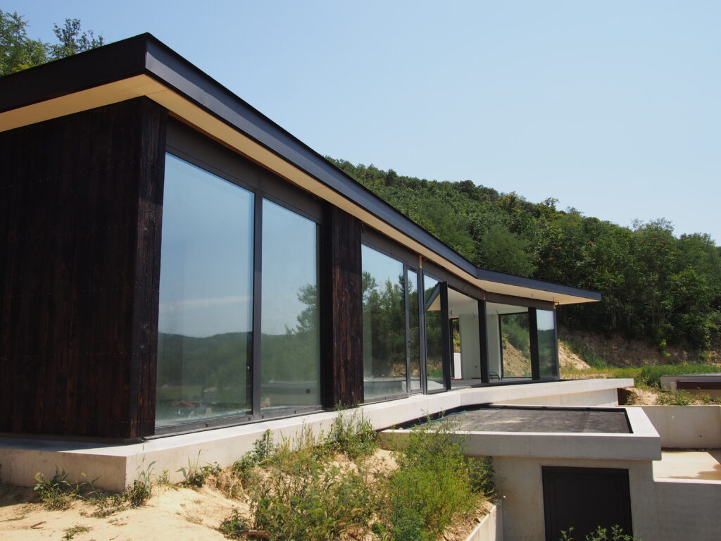 Maison contemporaine en ossature bois avec bardage bois brûlé et toiture terrasse EPDM