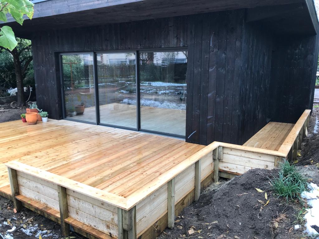 Extension en ossature bois brûlé avec terrasse en bois.